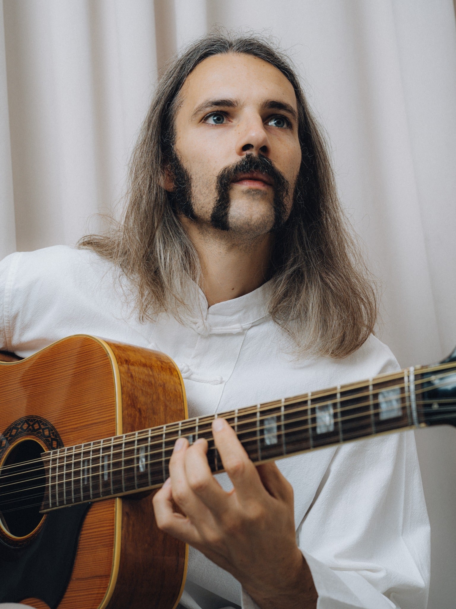 Progressiva Shirt in white, close-up while playing a twelve-string acoustic guitar