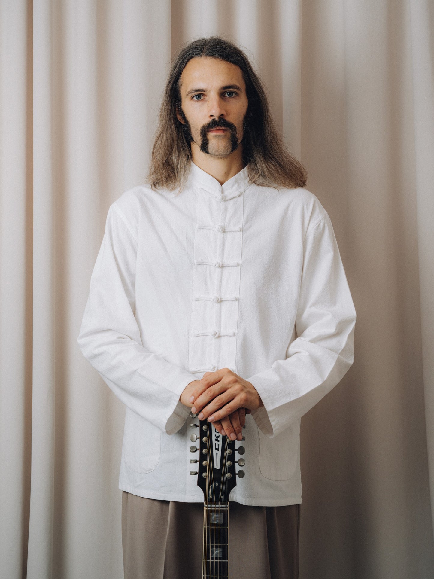 Progressiva Shirt in white with mandarin collar and knotted closures, front view on model